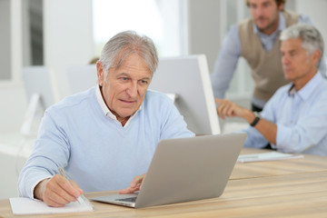 Fototapeta na wymiar Portrait of senior man working on laptop, training class