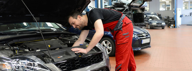car repair shop // Mechaniker repariert Motor eines Fahrzeuges in der Werkstatt