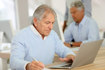 Portrait of senior man working on laptop, training class