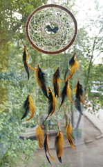 photo of a dreamcatcher made by hand, with using threads, beads and feathers rooster