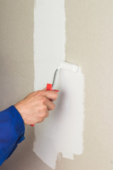 Man hand using paint roller on the wall with white color