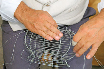 craftsman weaves wire vase with hands