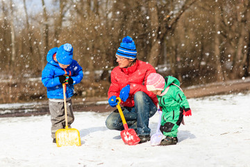 Fototapeta na wymiar father and kids digging snow in winter park