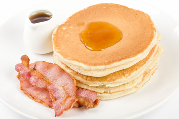 Pancakes, bacon and maple syrup on a white background.
