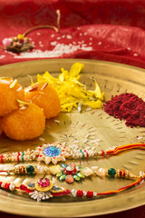Fototapeta na wymiar Closeup of a plate containing Rakhi and ladoo with sindoor and some flowers marking the religious celebration of Raksha Bhandan.