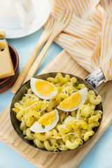 Fried pasta with boiled eggs, cheese and chives