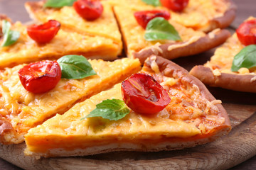 Slices of tasty cheese pizza with basil and cherry tomatoes on table close up