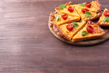Slices of tasty cheese pizza with basil and cherry tomatoes on table close up