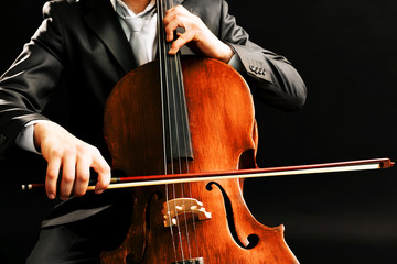 Man playing on cello on dark background