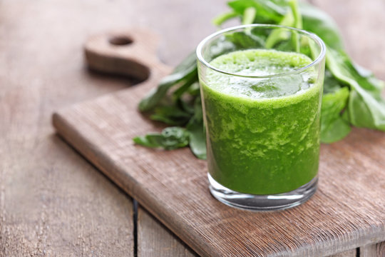 Glass of spinach juice on wooden table, closeup