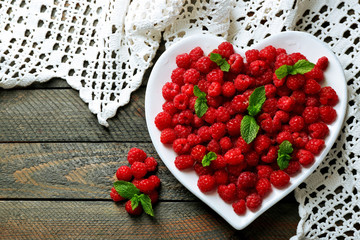 Sweet raspberries on plate, on wooden  background