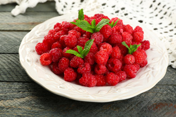 Sweet raspberries on plate on wooden  background