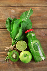 Green healthy juice with fruits and herbs on wooden table close up