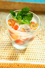 Glass of cold refreshing summer drink with berries and ice cubes on table close up