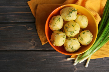 Boiled potatoes with greens in bowl on table close up