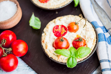 quiche with goat cheese, cherry tomatoes and basil on blue woode