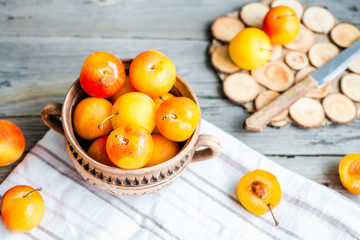 organic yellow plums in pottery on gray wooden table, rustic, to