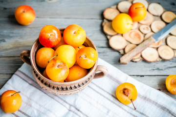 Fresh yellow plums in pottery on gray wooden table, rustic, farm