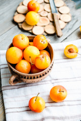 Fresh yellow plums in pottery on gray wooden table, rustic, farm