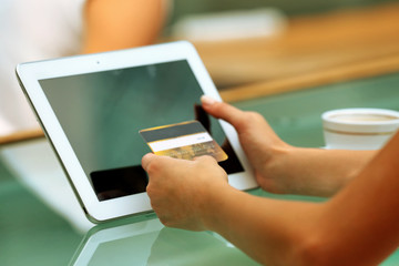 Female hands holding credit card with digital tablet on table close up