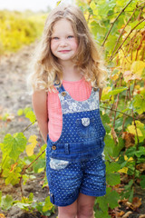 Blonde curly child girl in grape garden