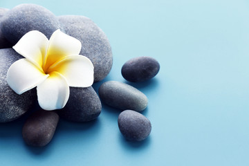 Obraz na płótnie Canvas Spa stones with flower on blue background