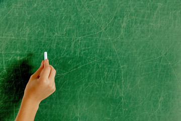 Female hand writing on blackboard with chalk, close up