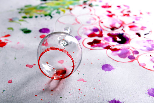 Wineglass of spilled wine with watercolors stains on paper background