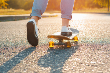 Woman skateboarding at sunrise. Legs on the skateboard