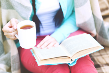 Young woman with book sitting on green grass outdoors