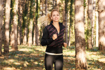 Beautiful young woman running through the park