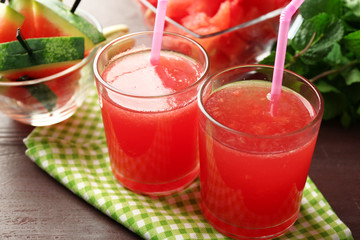 Cold watermelon drinks in glasses, on wooden table background