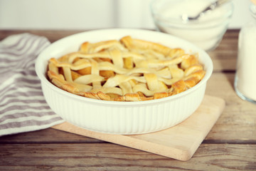 Homemade apple pie on wooden table, on light background