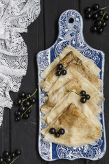 Pancakes with yogurt and black currant on a blackboard with lace  