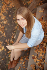 girl sitting on the steps of the wooden porch, autumn season