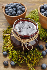 Jar of blueberry jam and bowls of blueberries