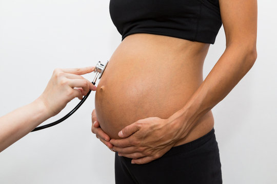 schwanger Frau lässt sich den Bauch untersuchen, mit einem Stethoskop