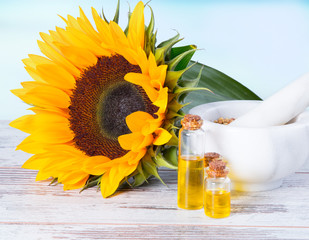 Sunflower oil with flower and seeds on wooden table with nature background