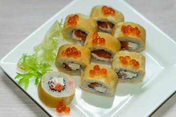 Close-up of a white plate with sushi set - Russian pancakes with