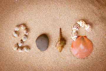 New Year 2016 sign with shell and stone on sand beach.