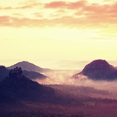Red daybreak. Misty daybreak in a beautiful hills. Peaks of hills are sticking out from foggy background, the fog is red and orange due to Sun rays.