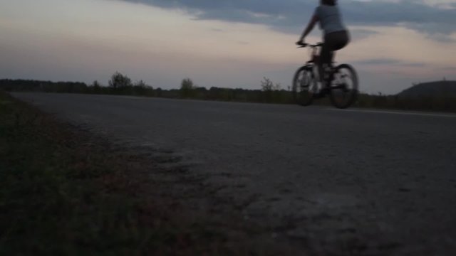 pair of cyclists ride on a rural road at evening, Zhiguli, Russia