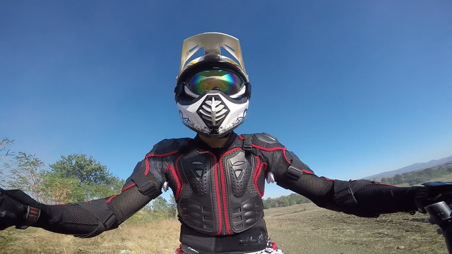 Point of View: Enduro rider in motorcycle protective gear riding bike on dirt track