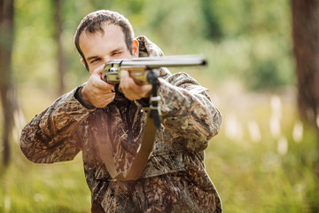 Fototapeta premium hunter with shotgun looking through binoculars in forest