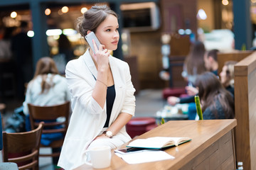 Young, beautiful girl in a white suit, sitting in the cafe at th