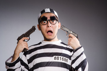 Young prisoner with handgun against gray