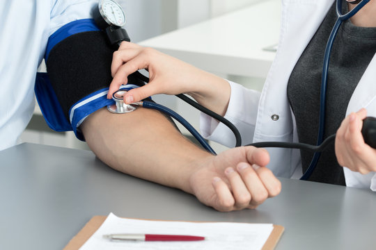 Female medicine doctor measuring blood pressure to her patient