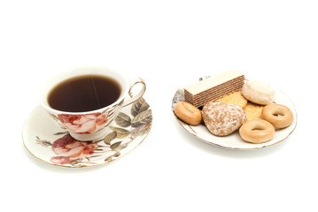 mug of tea and different sweets on white