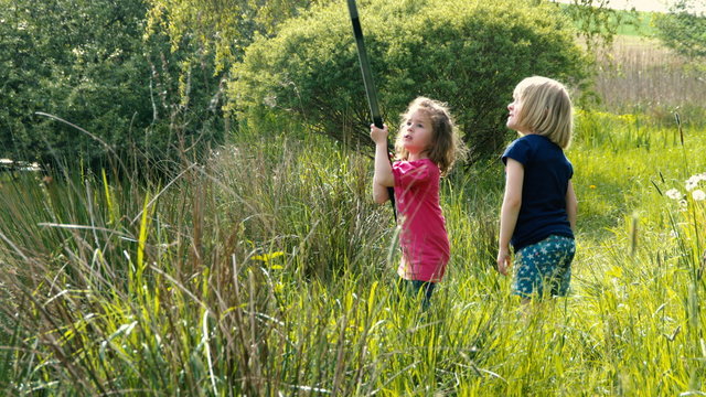 Zwei kleine M&auml;dchen angeln am Teich und ein Fisch bei&szlig;t fast an