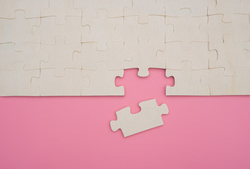 jigsaw puzzle with one piece loose on pink background